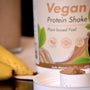 a container of protein shake next to two bananas