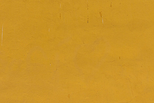 a man riding a skateboard down a street next to a yellow wall