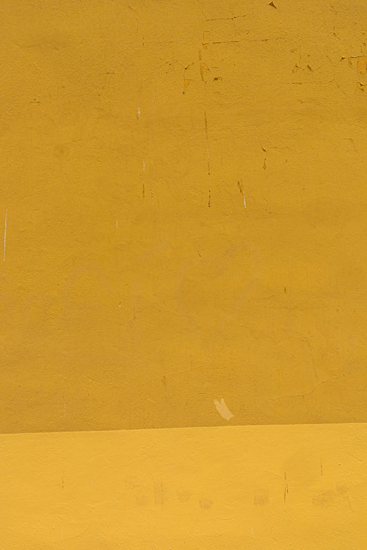 a man riding a skateboard down a street next to a yellow wall