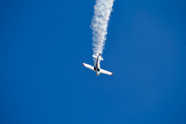 a plane with smoke coming out of it flying in the sky