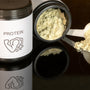 a jar of protein powder next to a spoon