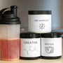 three containers of protein powder next to a blender
