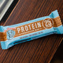 A protein bar rests on a wooden surface.